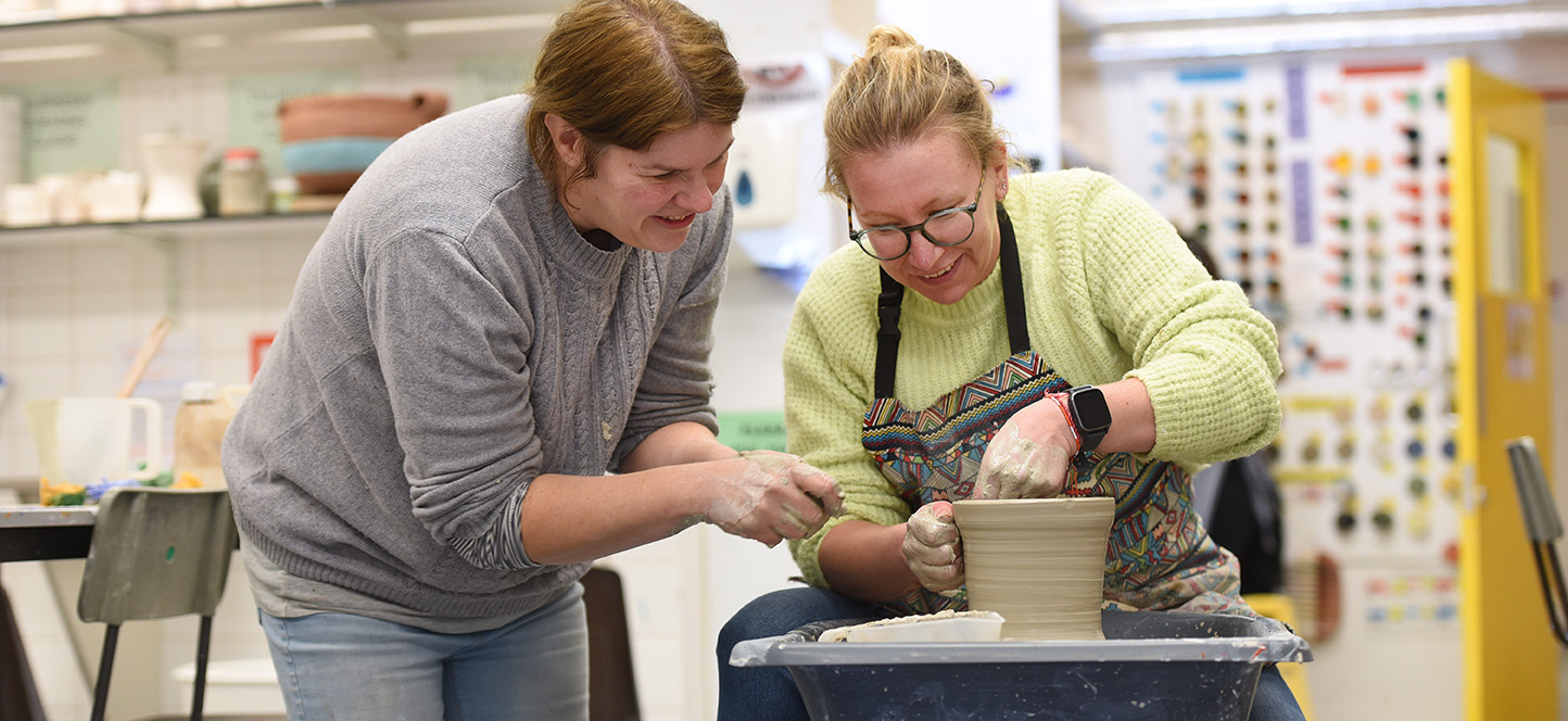 Two adults shaping a pot with clay at a Hills Road ceramics class in Cambridge